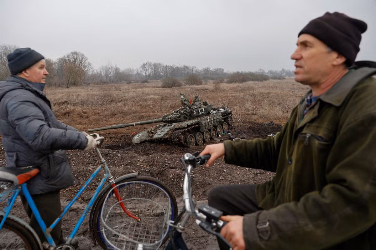 Cư dân địa phương đi gần một xe tăng bị bỏ lại tại làng Nova Basan, vùng Chernihiv, Ukraine ngày 1/4/2022. Ảnh: Reuters