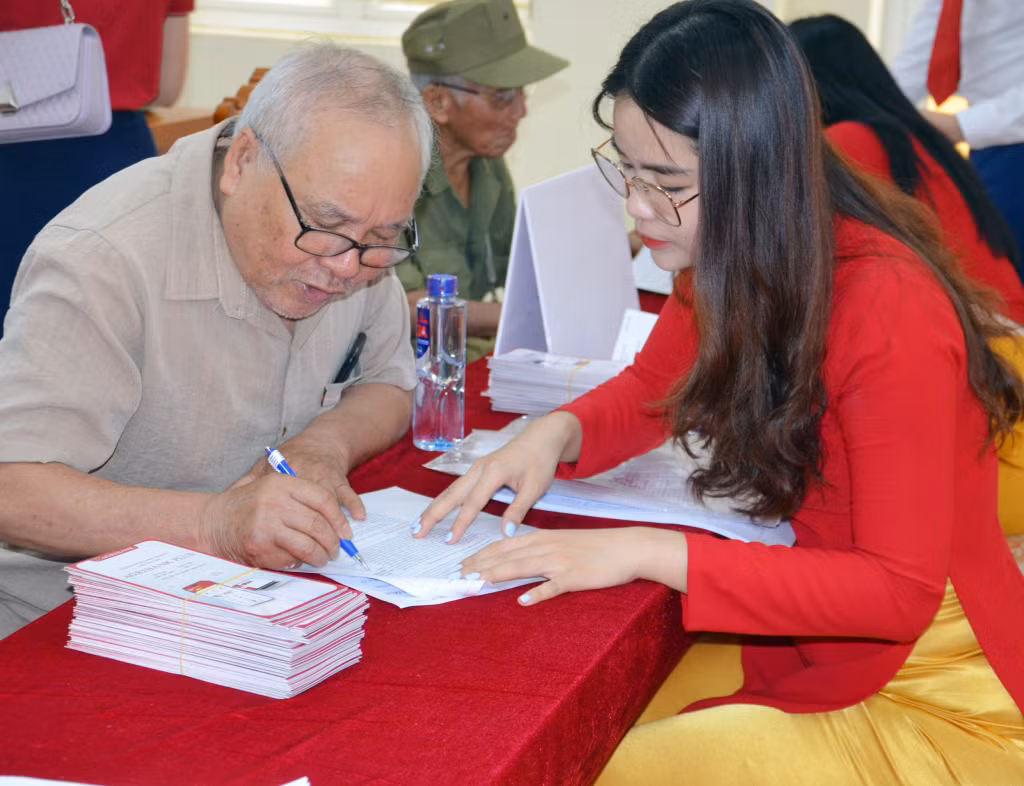 Cán bộ Ngân hàng Nông nghiệp và Phát triển nông thôn Chi nhánh Bãi Cháy hướng dẫn cán bộ hưu trí phường Việt Hưng (TP Hạ Long) ghi thay đổi thông tin nhận lương hưu qua tài khoản thẻ ATM. Ảnh: Dương Trường