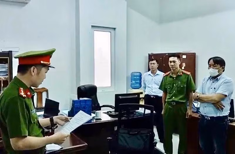 Trần Hữu Dũng (khoanh tay) nghe lệnh bắt bị can từ cơ quan chức năng.