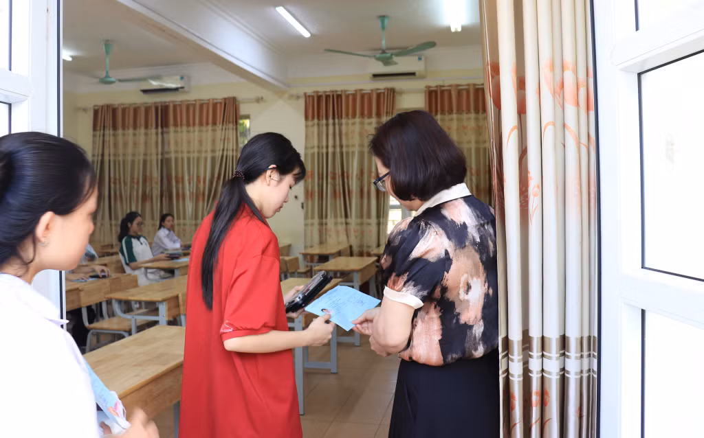 Cán bộ coi thi đọc tên và kiểm tra thông tin thí sinh trước khi vào phòng thi tại Hội đồng coi thi Trường THPT Hải Đảo (huyện Vân Đồn).