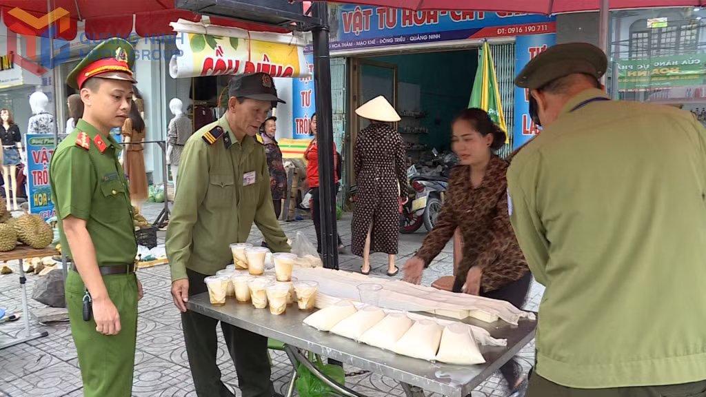 Lực lượng chức năng phường Mạo Khê nhắc nhở người dân thu dọn hàng hoá bày bán lấn chiếm vỉa hè.
