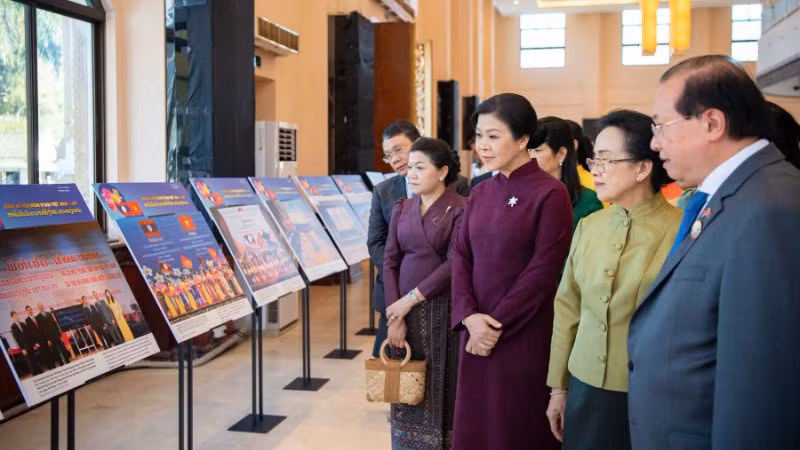 Phu nhân Ngô Phương Ly và Phu nhân Naly Sisoulith cùng các khách mời tham quan khu vực Triển lãm ảnh quan hệ Việt Nam-Lào. (Ảnh: Nguyễn Hồng)