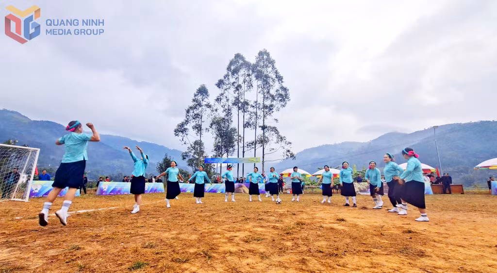 Các cầu thủ nữ diện trang phục dân tộc với sắc màu rực rỡ, tập trung khởi động giữa khung cảnh tuyệt đẹp của núi rừng Bình Liêu.