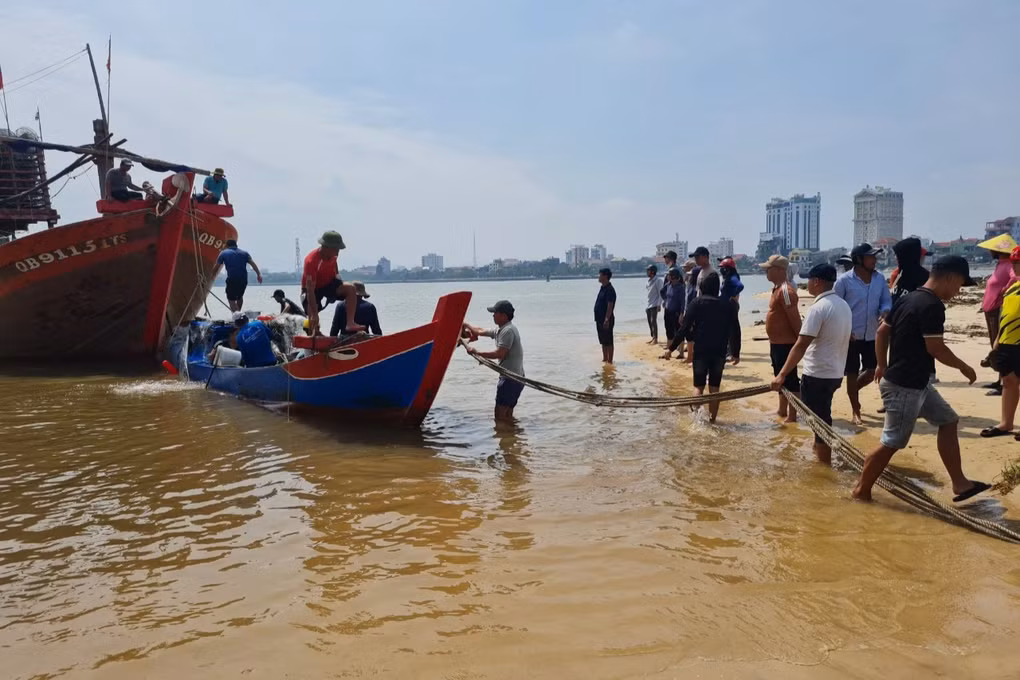 Chiếc thuyền nhỏ của bố con ông Phong được cứu hộ, lai dắt về bờ (Ảnh: Nhật Anh).
