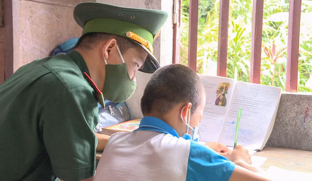 Cán bộ Đồn BPCK Hoành Mô dạy em Lý Gia Hưng học bài.
