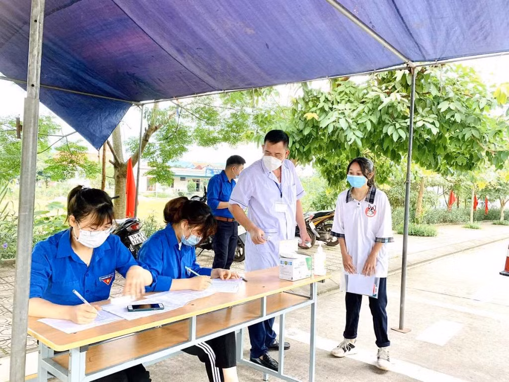 Đội TNTN tiếp sức mùa thi phối hợp với cán bộ y tế ghi chép thông tin của các thí sinh tại điểm thi Trường THPT Hải Đông (huyện Tiên Yên).