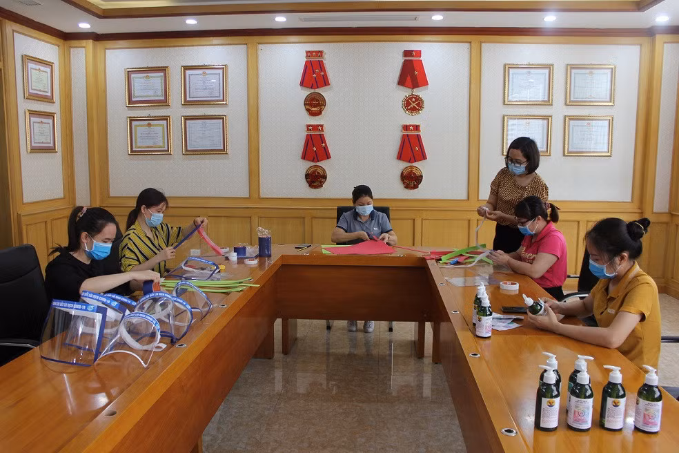 Cán bộ, hội viên phụ nữ Công ty CP 397 (Tổng Công ty Đông Bắc) làm mũ chắn giọt bắn, pha chế dung dịch rửa tay sát khuẩn.