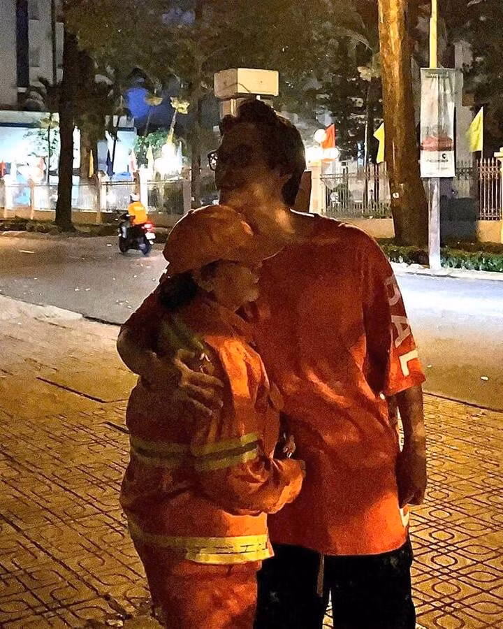 Hình ảnh Hà Anh Tuấn ôm chị nhân viên quét đường trong đêm giao thừa.