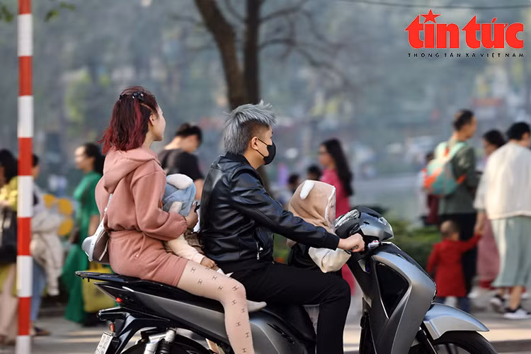 Nhiều gia đình đi xe máy kẹp 3, kẹp 4 (kèm theo trẻ nhỏ) nhưng không có bất kỳ ai đội mũ bảo hiểm.