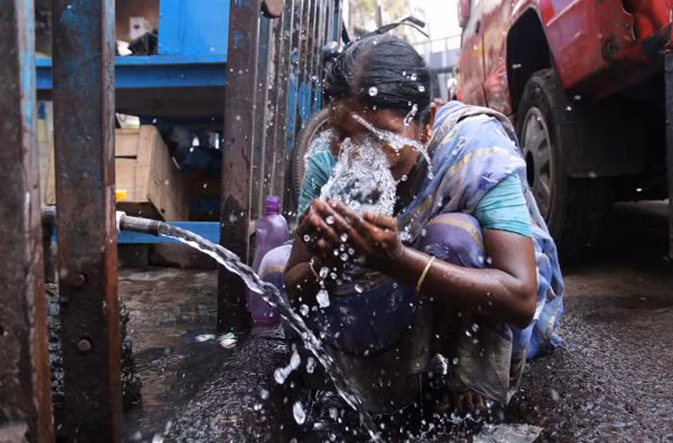 Một phụ nữ vẩy nước lên mặt để giảm nhiệt tại Kolkata. (Ảnh: CNN)