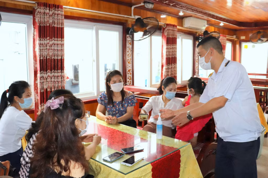 Nhân viên tàu du lịch trên Vịnh Hạ Long hướng dẫn du khách sát khuẩn, đảm bảo yêu cầu phòng, chống dịch Covid-19. Ảnh: Hoàng Quỳnh