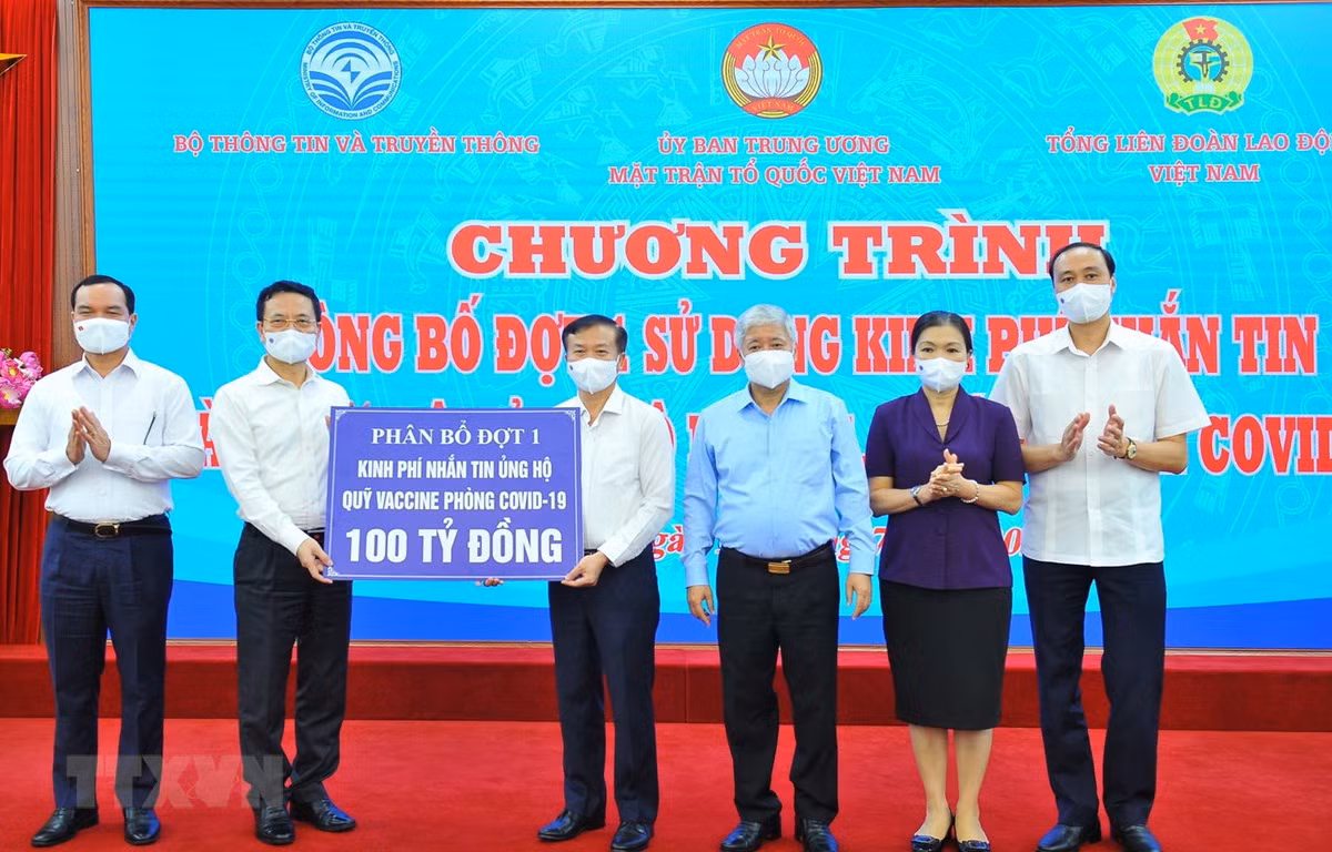 Bộ trưởng Bộ Thông tin và Truyền thông Nguyễn Mạnh Hùng (trái) trao số tiền nhắn tin 100 tỷ đồng ủng hộ Quỹ vaccine phòng COVID-19 (phân bổ đợt 1) cho Giám đốc Ban quản lý Quỹ vaccine phòng COVID-19 Nguyễn Quang Vinh. (Ảnh: Minh Đức/TTXVN)