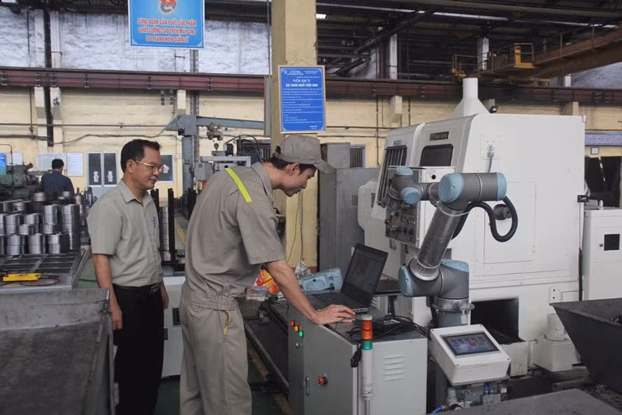 Công nhân lập trình cho hệ thống robot vận hành máy CNC.