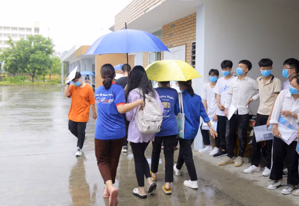 Lần lượt từng sĩ tử được các anh chị, các bạn TNTN che ô sau ra khỏi khu vực trường thi trong cơn mưa rào nặng hạt, khi kết thúc thời gian làm bài.
