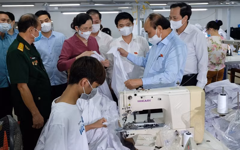 Ngày 23/7, Chủ tịch nước Nguyễn Xuân Phúc đến thăm doanh nghiệp may mặc Hoàng Tuyên tại tỉnh Hà Nam, do thương binh làm kinh tế giỏi Hoàng Văn Tuyên làm chủ. (Ảnh: Đào Phương)
