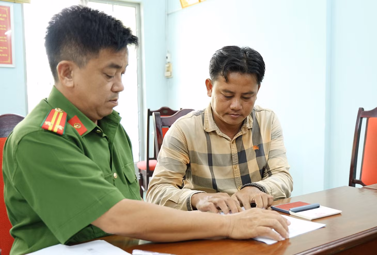 Bị can Dưỡng ký nhận các Quyết định và Lệnh bắt tạm giam sau khi đánh trọng thương con chủ quán nhậu. Ảnh: Vũ Tiến