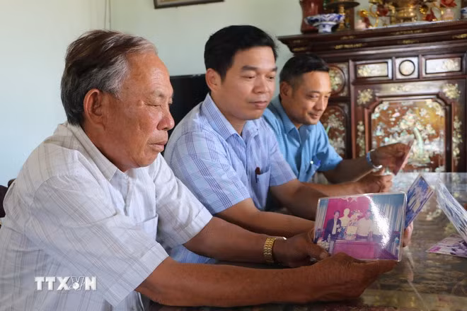 Nguyên Bí thư Đảng ủy xã Phổ Khánh (giai đoạn 2000-2010) Nguyễn Đức Thọ (bìa trái) xem lại tấm ảnh được chụp cùng nguyên Chủ tịch nước Trần Đức Lương. (Ảnh: Đinh Hương/TTXVN)