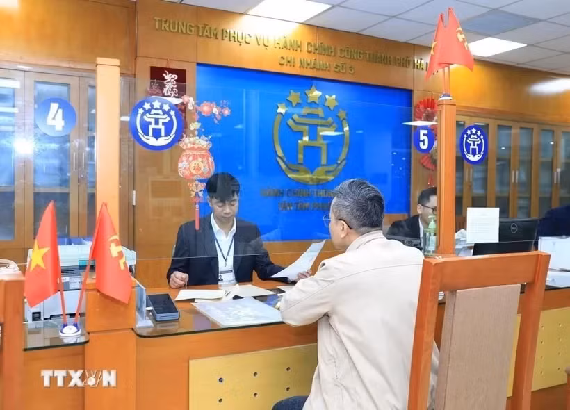 Cán bộ, công chức Trung tâm Phục vụ hành chính công thành phố Hà Nội-Chi nhánh số 3 hướng dẫn người dân hoàn thiện hồ sơ thủ tục hành chính. Ảnh: TTXVN.