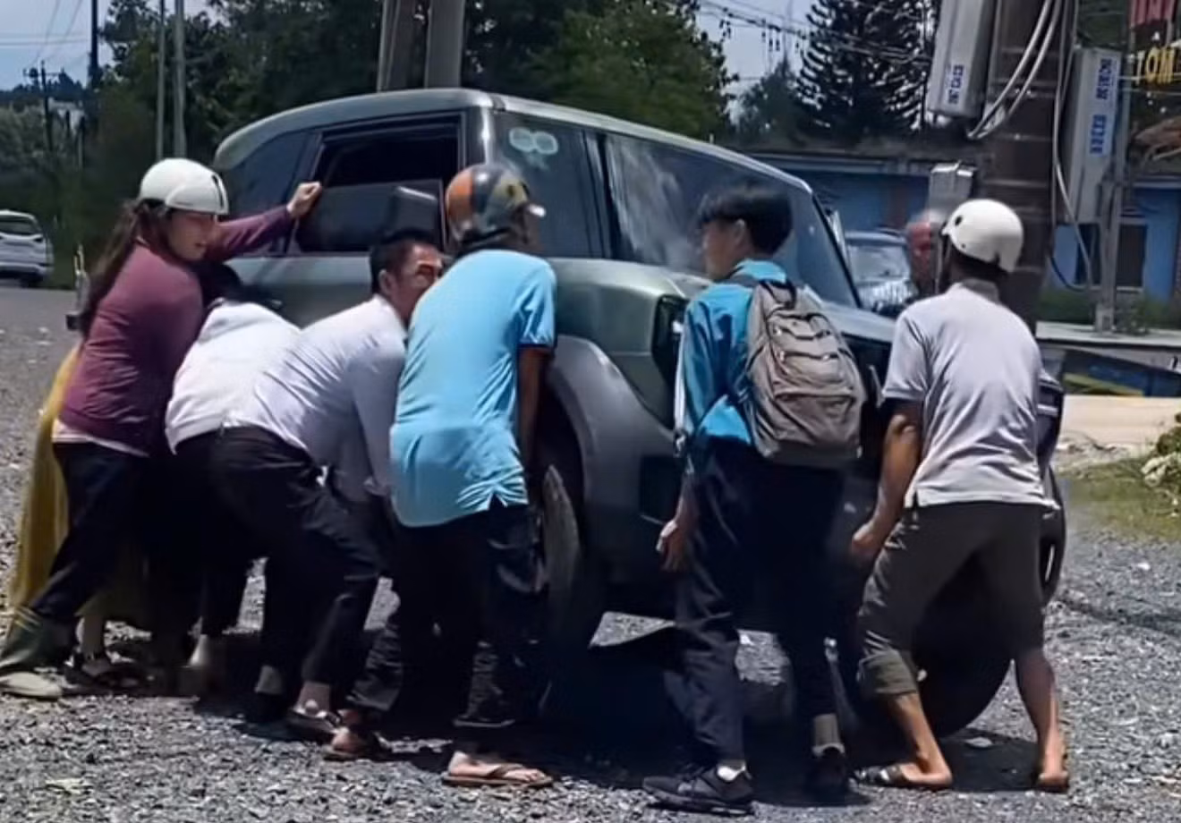 Nhiều người dân hợp sức nâng bổng ô tô con cứu nữ sinh mắc kẹt dưới gầm sau tai nạn. Ảnh: Hoài Thanh