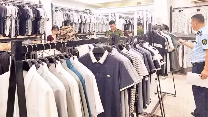 Lực lượng chức năng kiểm tra cửa hàng thời trang kinh doanh các sản phẩm giả mạo thương hiệu quốc tế tại phường Tây Tựu, thành phố Hà Nội. (Ảnh: TUẤN NGỌC)