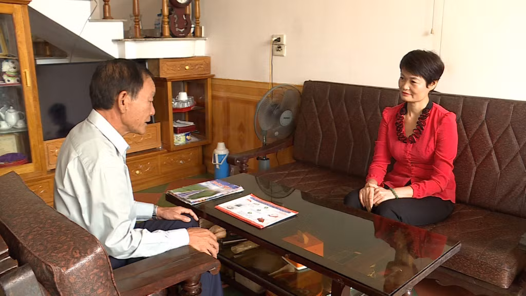 Ông Phạm Văn Biên (bên trái) chuẩn bị nhiều tài liệu để tuyên truyền Luật Giao thông cho người dân.