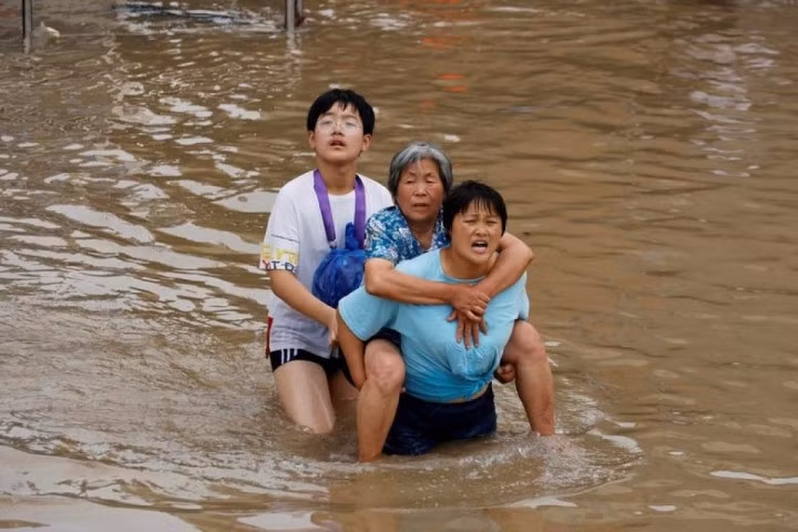 Người phụ nữ trẻ cõng một người phụ nữ lớn tuổi qua khu vực bị ngập nước ở Trịnh Châu, Hà Nam, Trung Quốc, ngày 23/7/2021.