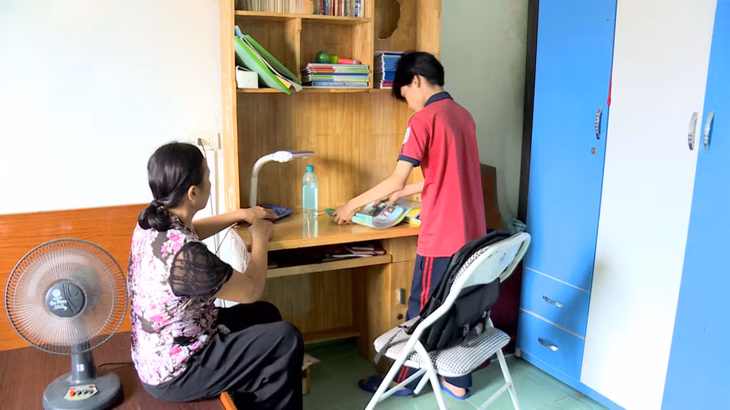 Bà Vũ Thị Mai (phường Hà Lầm, TP Hạ Long) cùng con trai sắp xếp lại góc học tập sau bão số 3.