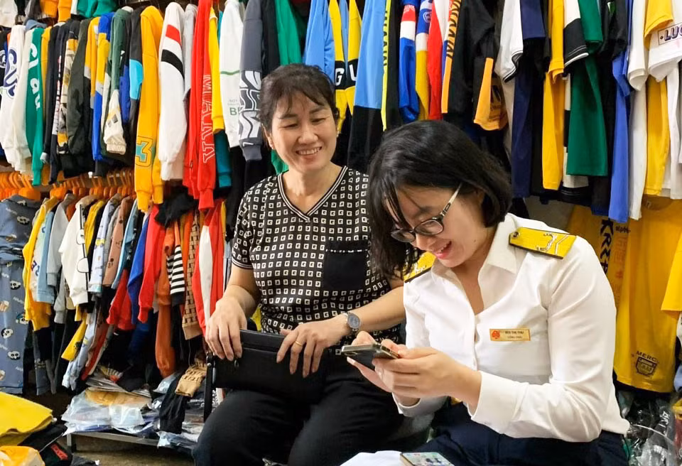 Cán bộ Chi cục Thuế TX Đông Triều hướng dẫn hộ kinh doanh nộp thuế qua ứng dụng eTax Mobile.