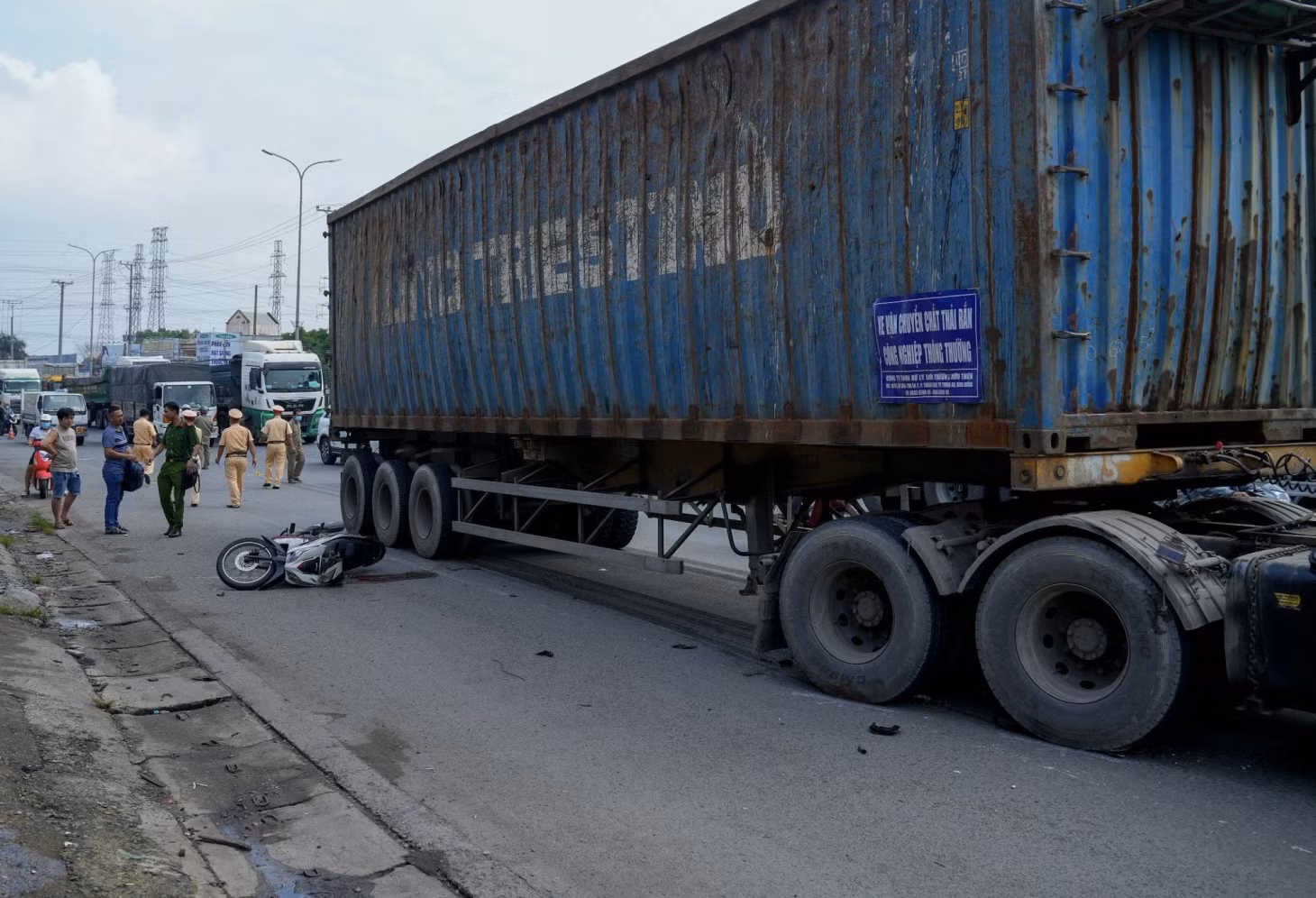 Xe máy đổ ra đường khiến nạn nhân ngã trúng bánh xe đầu kéo.