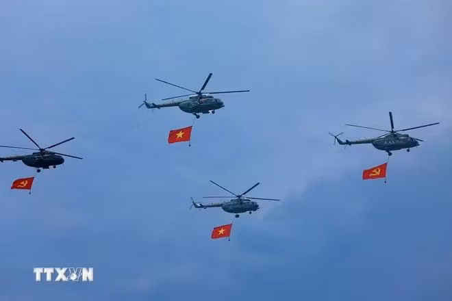 Máy bay trực thăng mang cờ Đảng, cờ Tổ quốc bay qua Lễ đài. (Ảnh: Dương Giang/TTXVN)