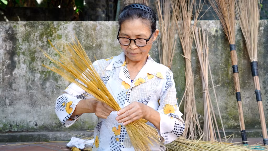 Bà Bùi Thị Mận (xã Yên Đức, TX Đông Triều) bện những chiếc chổi rơm truyền thống.
