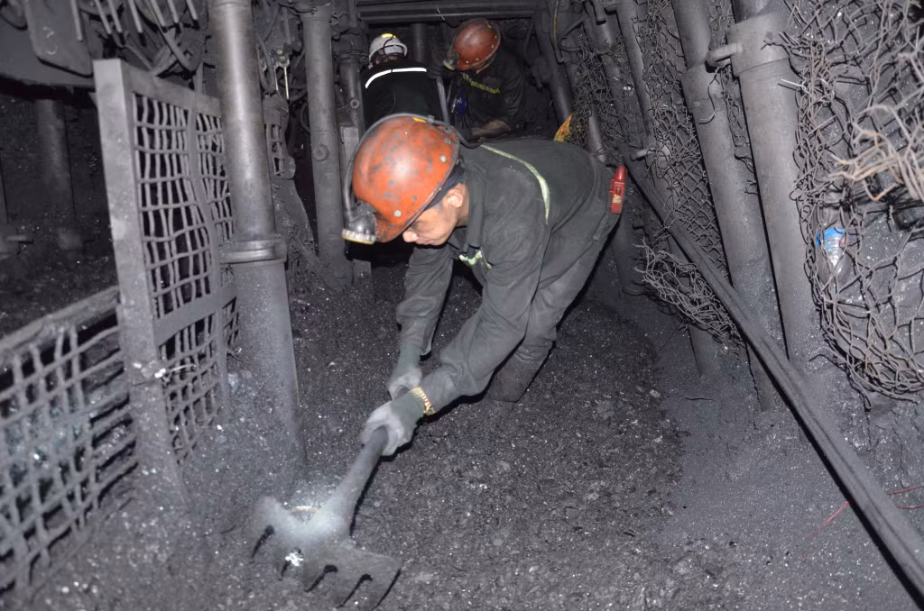 Thợ lò khao than xuống máng trượt để chuyển ra ngoài.