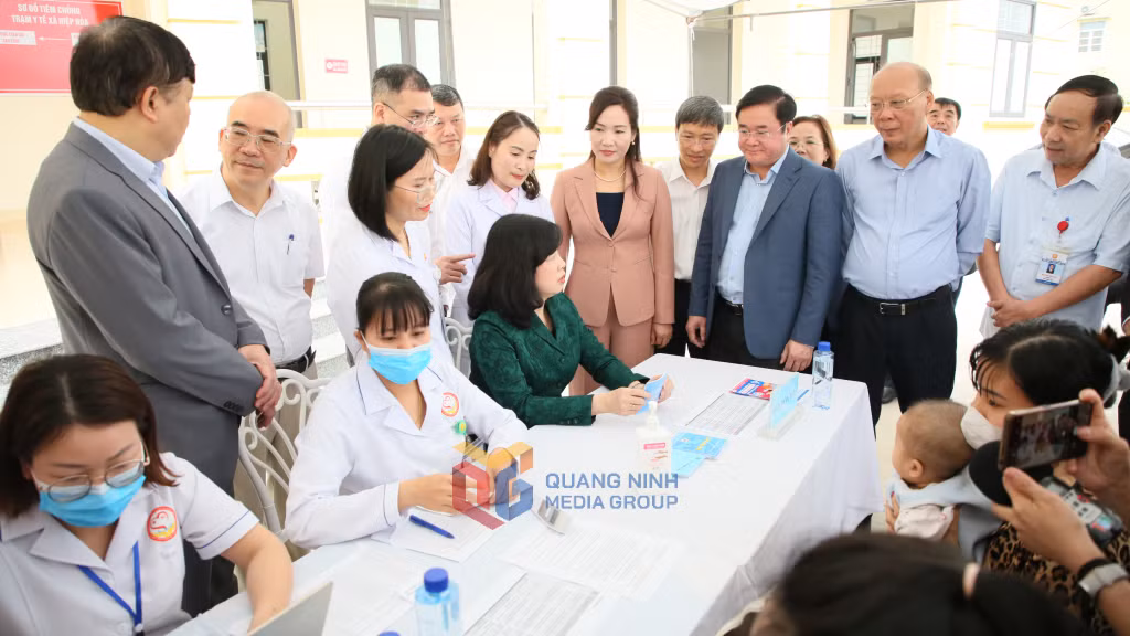 Bộ trưởng Đào Hồng Lan kiểm tra sổ tiêm chủng tại khu vực đón tiếp trẻ đến tiêm vắc-xin sởi tại Trạm Y tế xã Hiệp Hoà.