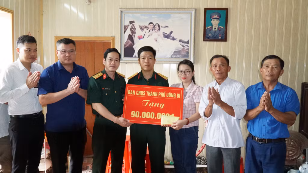 Thượng tá Trần Anh Tuấn, Chính trị viên Ban CHQS TP Uông Bí trao số tiền 90 triệu đồng cho gia đình Trung tá Nguyễn Tiến Định.