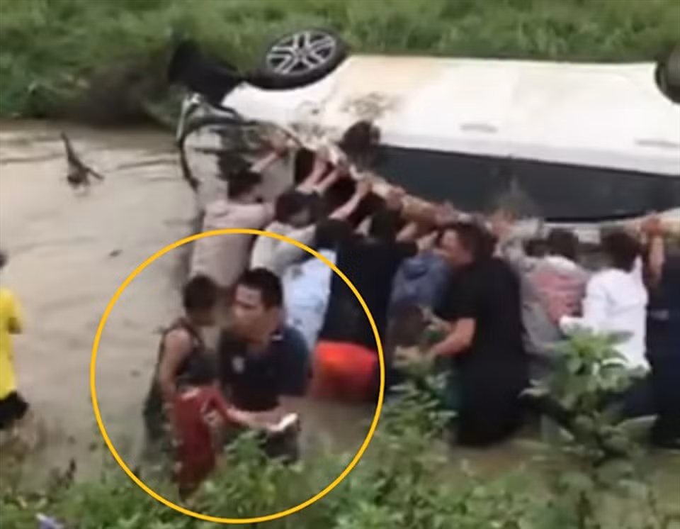 Người dân hợp sức cứu 2 em bé mắc kẹt trên chiếc ôtô mất lái lao xuống mương. Ảnh cắt từ clip