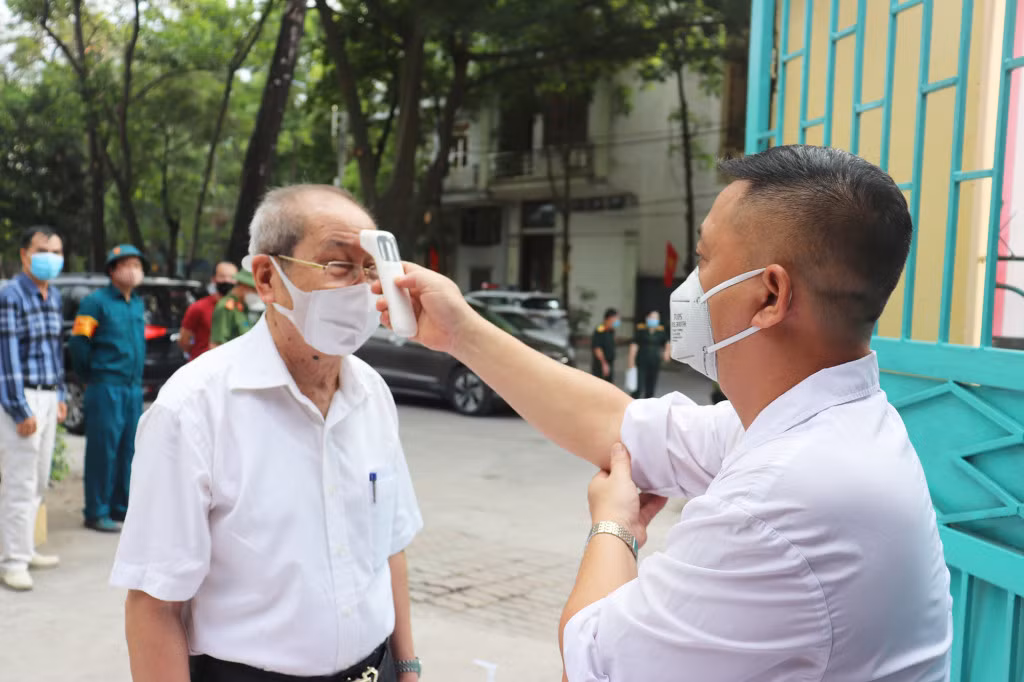 ...thực hiện đo thân nhiệt trước khi vào bỏ phiếu bầu cử.
