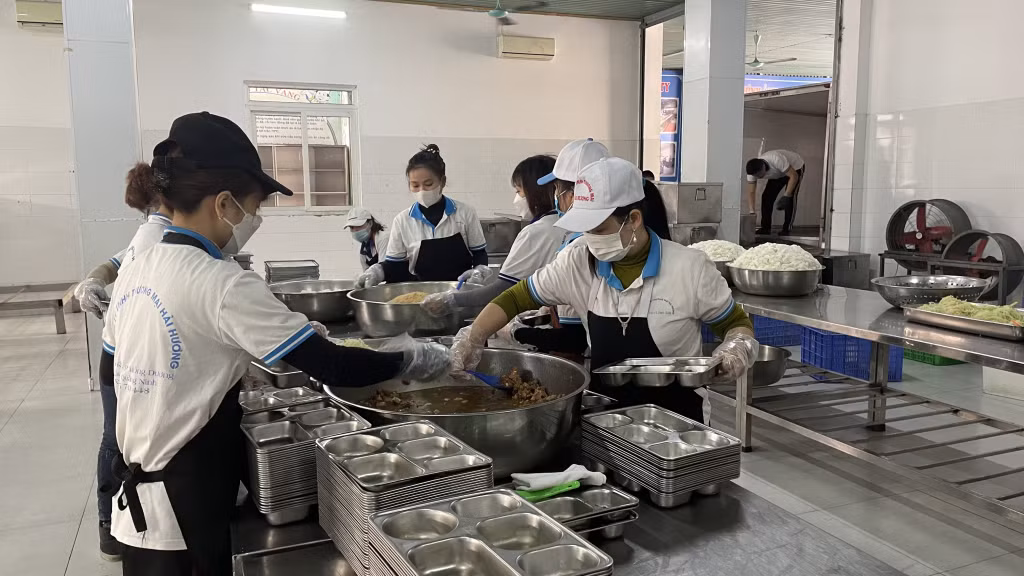 Nhân viên Công ty TNHH Thương mại Hải Hương chia suất ăn bán trú cho học sinh.