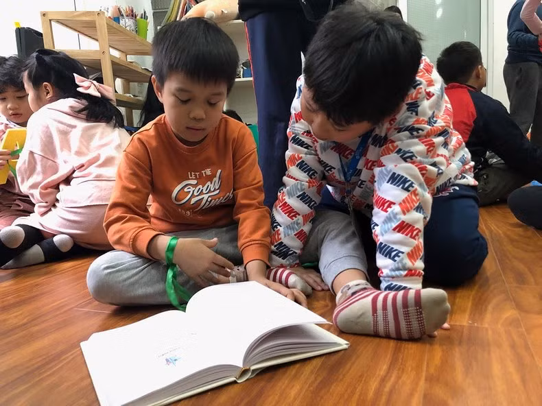 Hai em nhỏ đang đọc cuốn "Trò chơi của trẻ em ở Bắc Kỳ”.