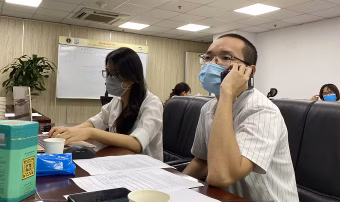 Bác sĩ Bùi Thanh Phúc, Bệnh viện Hữu nghị Việt Đức (bìa phải), tư vấn qua điện thoại cho bệnh nhân Covid-19 ở TP HCM chiều 26/7. Ảnh: Mạnh Cường