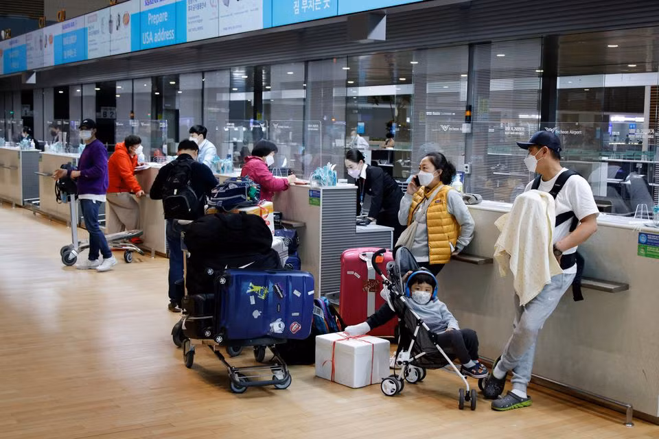 Hành khách đeo khẩu trang trong lúc đợi làm thủ tục ở sân bay quốc tế Incheon ngày 25/3. Ảnh: Reuters