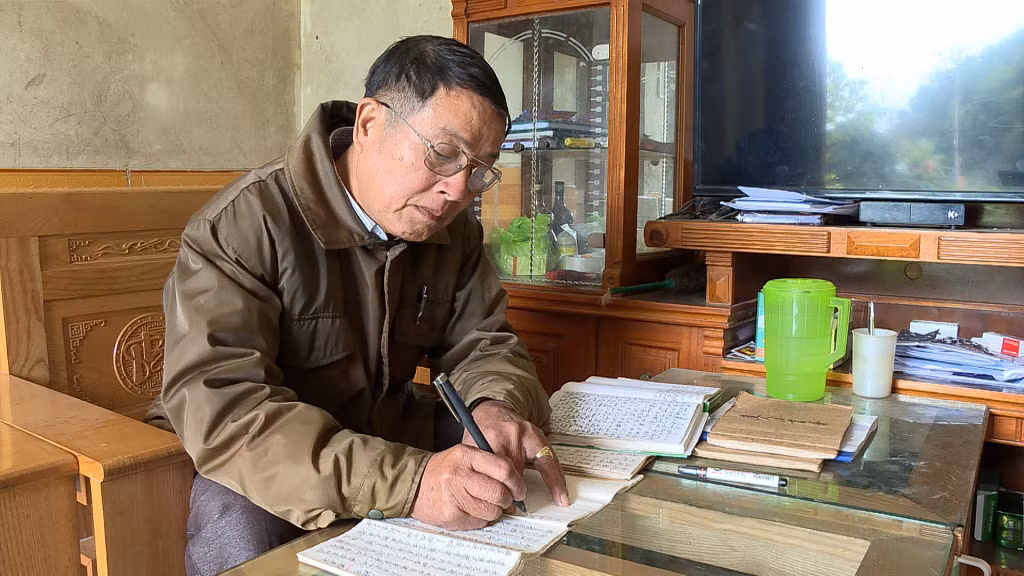 Nghệ nhân dân gian Đặng A Mản (thôn Nam Hả Trong, xã Nam Sơn, huyện Ba Chẽ) đang dịch thuật sách Nôm Dao.