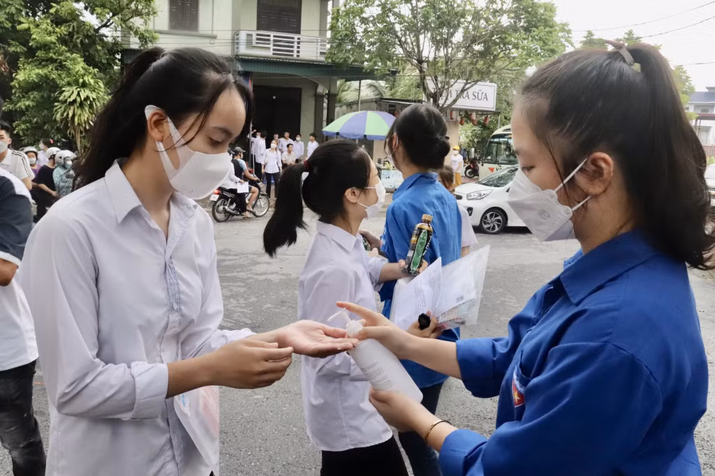 Thanh niên tình nguyện hướng dẫn thí sinh rửa tay sát khuẩn trước khi vào trường thi.