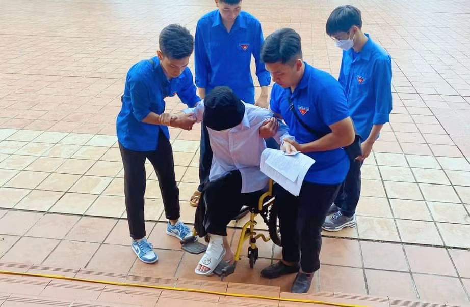 Lực lượng thanh niên tình nguyện tiếp sức mùa thi đã có mặt tại tất cả các điểm thi để hỗ trợ, đồng hành cùng sĩ tử đi thi. Trong ảnh: Tình nguyện viên TX Đông Triều hỗ trợ thí sinh do bị tai nạn, phải ngồi xe lăn, không thể tự vào phòng thi tại điểm thi THPT Nguyễn Bình.