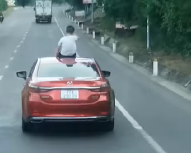 Hình ảnh em bé ngồi trên nóc xe ôtô khi đang lưu thông (Ảnh cắt từ clip).