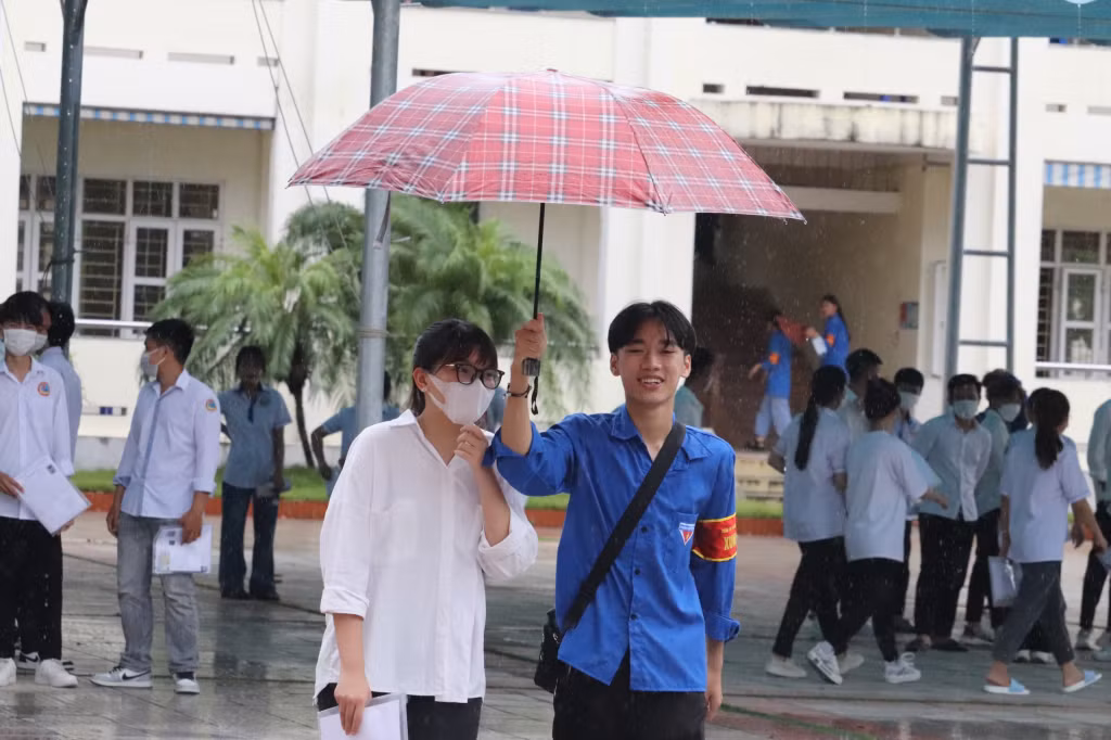 Lực lượng thanh niên tình nguyện tiếp sức mùa thi che ô cho các thí sinh rời điểm thi.