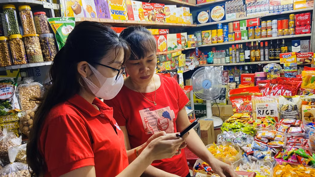 Viettel Quảng Ninh hướng dẫn chủ cửa hàng tạp hóa Thu The tại chợ Hạ Long I cài đặt ứng dụng Viettel Money để thanh toán không dùng tiền mặt. (Ảnh: Hoàng Nga).