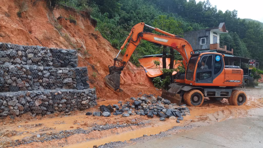 Chính quyền địa phương huy động máy xúc khắc phục những điểm sạt lở taluy dương đảm bảo người dân đi lại an toàn.