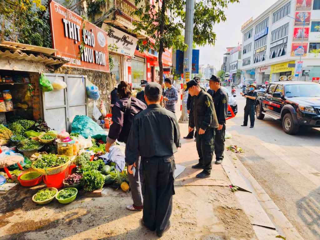 Lực lượng chức năng thực hiện tháo dỡ các ô dù, vật dụng lấn chiếm trên vỉa hè.