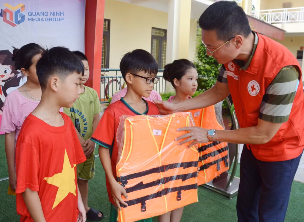 Phó Chủ tịch Hội Chữ thập đỏ tỉnh Nguyễn Tuấn Anh tặng áo phao cho học sinh tham gia lớp học bơi miễn phí tại Trường tiểu học Phong Hải (TX Quảng Yên).