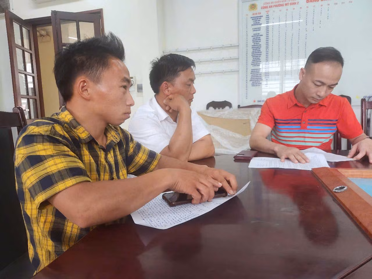 Anh Giàng Hồ (áo ca rô kẻ vàng) đến Công an phường Mỹ Đình 2 trình báo, sáng 16.6. Ảnh: Đặng Tiến